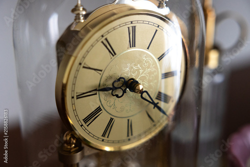 Photography An old brass clock, time, clock face with roman numerals under a glass dome