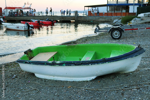 Konstfotografi Green fishing boat on a rocky beach near a seaside harbor