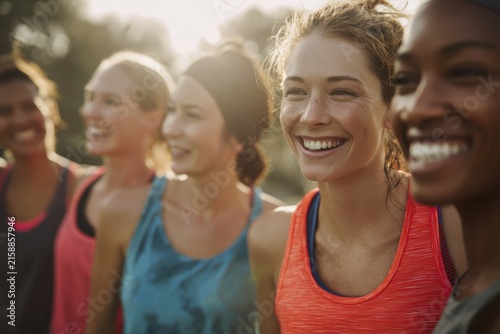 Close up group of enthusiastic runners laughing together in local park wearing bright running gear and fitness trackers, authentic community bonding perfect for teamwork and wellness concept
