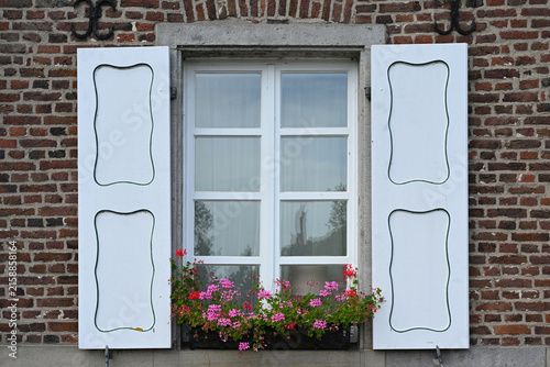 Buntes Holzfenster mit Sonnenladen in Zons, Deutschland
