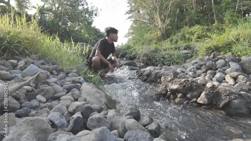 Man Washing His Face in a Natural Stream and Looking Up