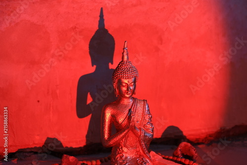 Buddha in red light casting a shadow