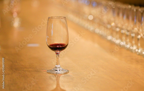 Glass of red wine placed on wooden table with out-of-focus empty wine glasses backdrop
