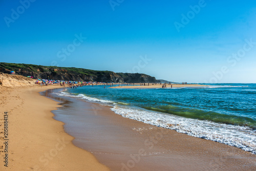 Waves rolling onto Praia das Furnas beach with cliffs and swimmers