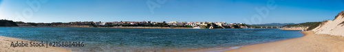 Fotografía Panoramic view of the Mira River estuary and the town of Vila Nova de Milfontes, showing the fortress, waterfront houses, bridge and sandy beach curving along the shoreline under a clear blue sky
