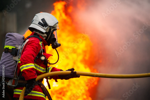 Fotografía Firefighter team spraying water to extinguish fire in industrial zone