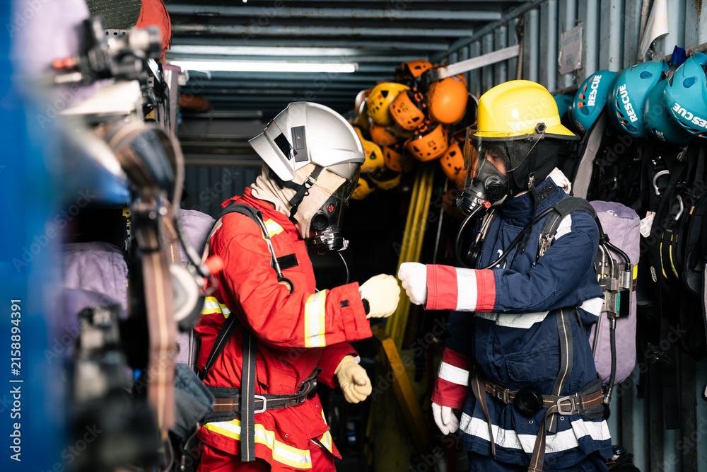 Fototapeta premium Two firefighters bumping fists in station locker room showing teamwork