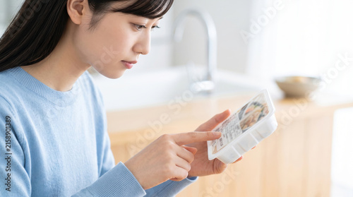 Plakat キッチンで冷凍食品やレトルト食品の成分表示を確認する女性