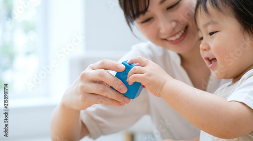 部屋で子供と一緒に積み木で遊ぶ笑顔の母親