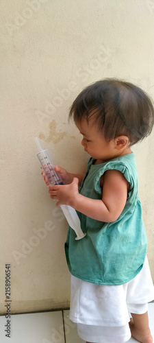 Foto Bright Indonesian baby girl having a fun playtime alone on the house porch
