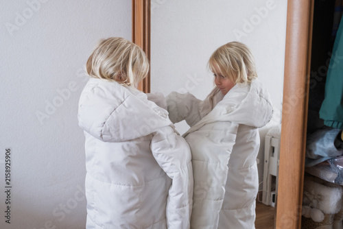 Fotografie Little Girl Trying on an Oversized Striped Shirt in Front of a Mirror