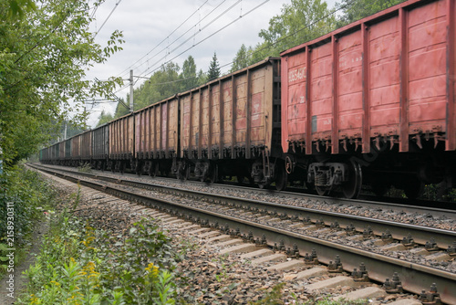A freight train transports construction materials and various products. Railway transport. Freight transportation by rail. Railway tracks. A railway train is rushing along the railway.