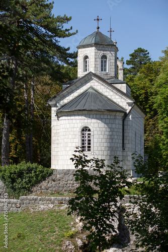 Stone Church in Forested Mountain Landscape With Bell Tower and Pine Trees
