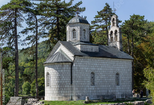 Stone Church in Forested Mountain Landscape With Bell Tower and Pine Trees