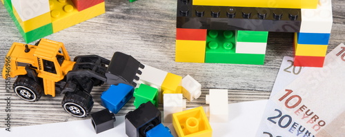 Houses made of toy blocks, miniature excavator, mortgage agreement form and euro banknotes. Financing building or purchase of real estate