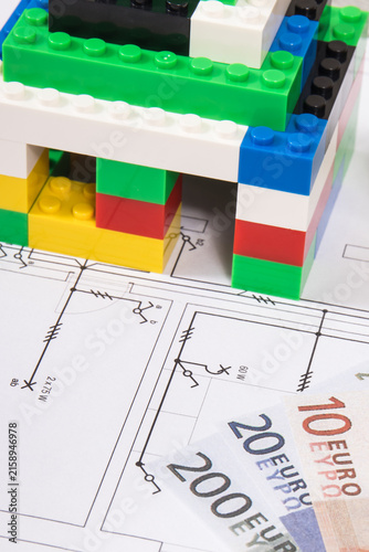 Small house made of toy blocks, housing plan with electric installation and euro banknotes. Building or renting home