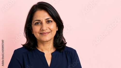Empathetic South Asian female manager with warm smile representing supportive leadership and positive workplace relationships, with pink copy space for HR marketing