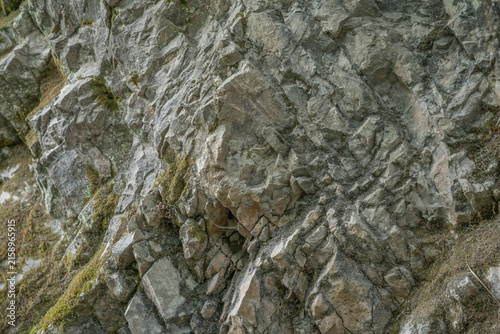 close up of rocky textured surface with natural moss and cracks on stone cliff wall