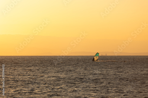 Cuadro en lienzo A lone windsurfer glides across the calm waters of the Adriatic Sea just before sunrise, with a golden sky providing a stark and beautiful backdrop