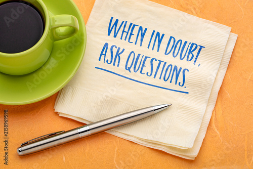 When in Doubt, Ask Questions. Inspirational handwritten message on a napkin with coffee and pen, encouraging curiosity, critical thinking, learning, and better decisions.