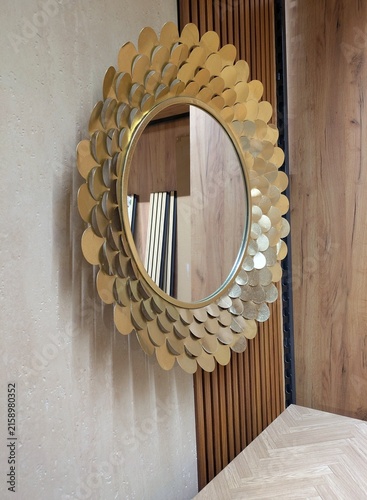 Foto Espejo decorativo redondo con un marco dorado de piezas de metal con forma de pé