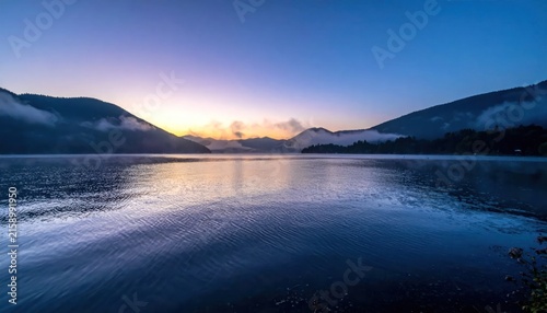 Calm lake at sunrise with mountain reflection background.