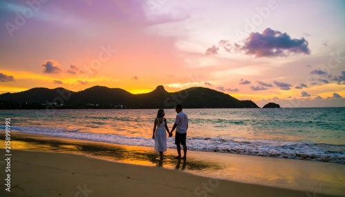 Couple holding hands on tropical beach at sunset