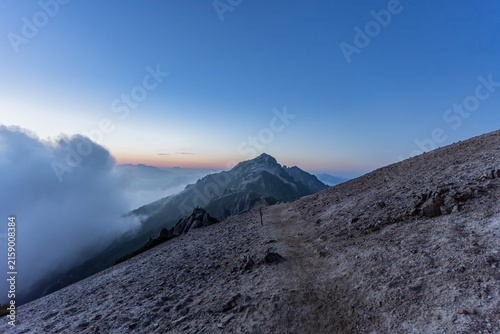 Mountain trail leading toward granite peak at dawn, Japan Alps
