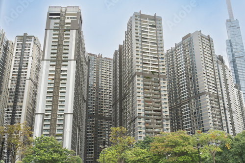 Modern high-rise residential apartment towers towering over green trees, with Landmark 81 visible in the background in Ho Chi Minh City, Vietnam.