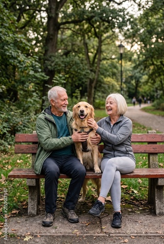 Happy senior couple relaxing with golden retriever in green park