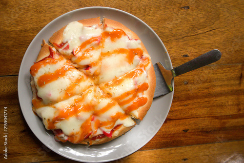 Homemade pizza with melted cheese and spicy sauce drizzle on plate