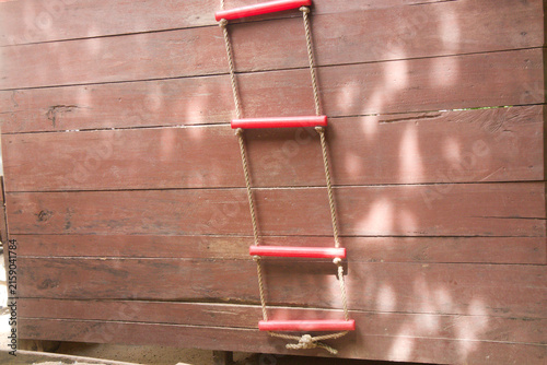 Red rope ladder hanging against wooden wall