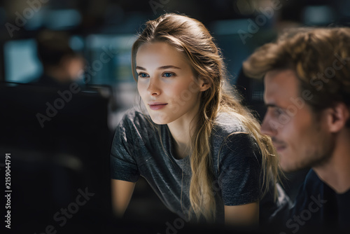 Female trainer teaches male colleague using AI software at shared office desk