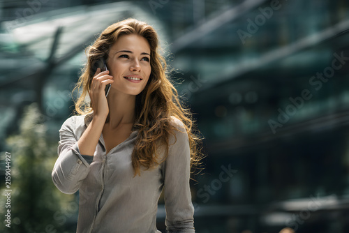 Woman walking outdoors taking phone call while working