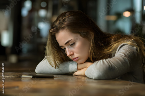 Young woman turning off her phone and placing it face down on a table