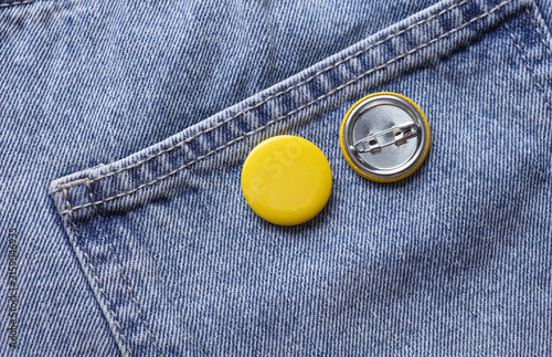 Yellow button badge pinned on blue jeans
