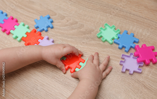 Baby hand plays with Plastic construction puzzle on a table. Games for developing toddlers logic and motor skills