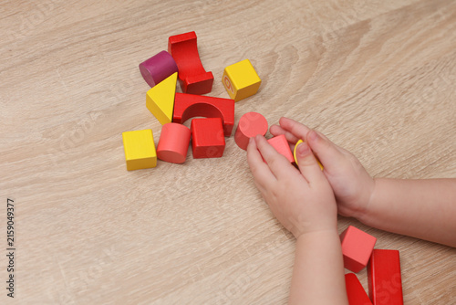 Baby Hands playing with wooden colored cubes on a table. Motor skills development.