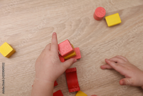 Baby Hands playing with wooden colored cubes on a table. Motor skills development.