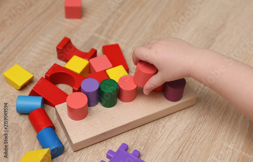 Toddler plays with a wooden color sorter. Develop toddler's logic and motor skills.