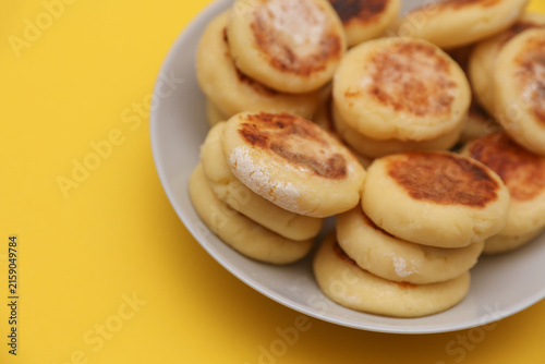 Homemade delicious syrniki, cheese pancakes in a plate on yellow background