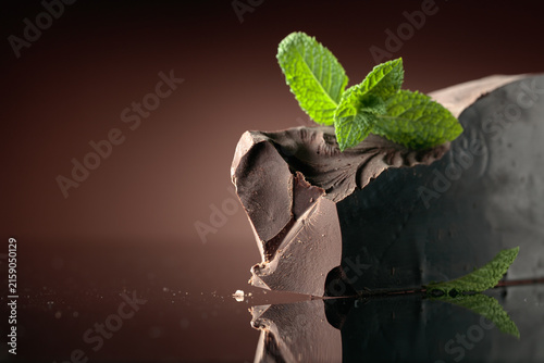 Obraz na plátně Large piece of dark bitter chocolate with mint on a black reflective background