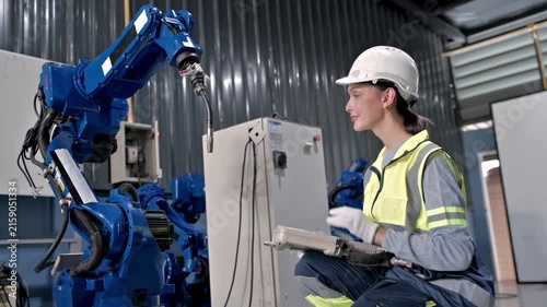 Industrial Robot and Engineer: A female engineer in safety gear operates an industrial robot arm in a modern factory setting, symbolizing advanced automation and manufacturing processes.