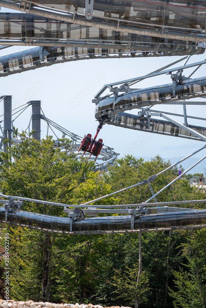 Fototapeta premium Tourist Riding a Suspended Mountain Adventure Ride Above Bay of Kotor, Montenegro, Scenic Summer Travel and Thrill Attraction
