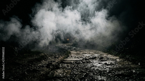 Dramatic night scene of thick white smoke and steam billowing over a rough muddy ground with distant light in background atmosphere.