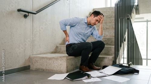 Middle-aged businessman sitting on stairs stressed from work pressure and burnout