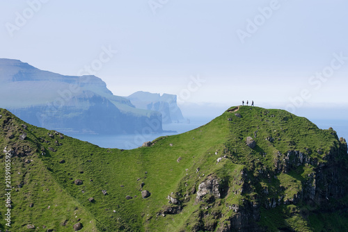 Travelers Hiking on Mountains to Kallur Lighthouse, Kalsoy Island, Faroe Islands in Summer
