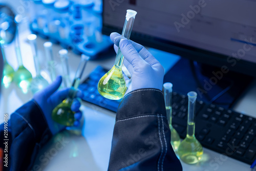 Cuadro en lienzo Gloved hands inspecting yellow volumetric flask at laboratory bench