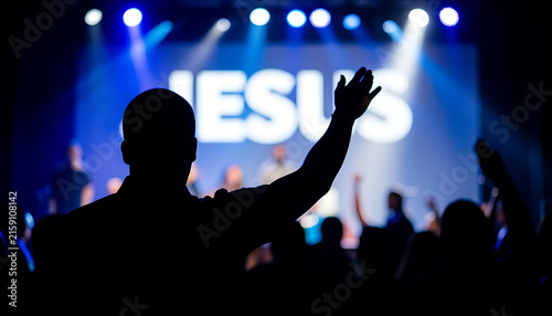 Concert crowd silhouetted under blue stage lighting in worship