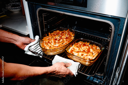 a man removing baked macaroni and cheese from the oven